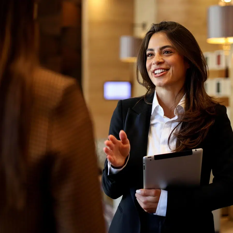 Femme en costume avec tablette souriant.