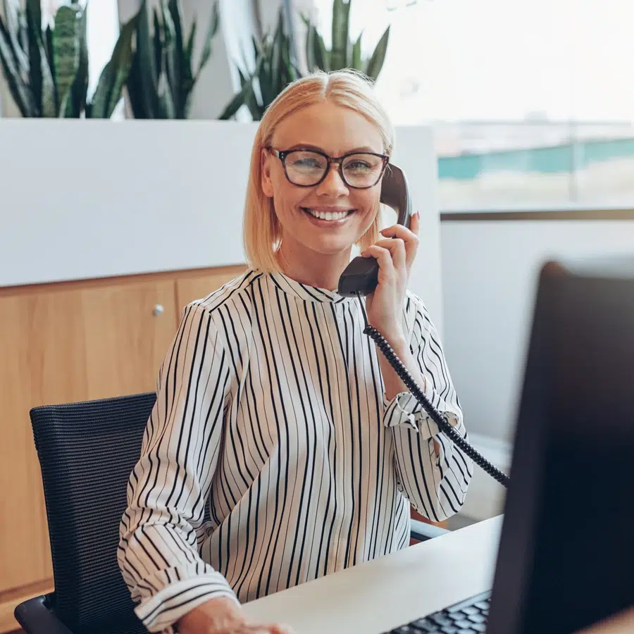 Femme au bureau avec téléphone Femme souriante au téléphone dans un bureau.